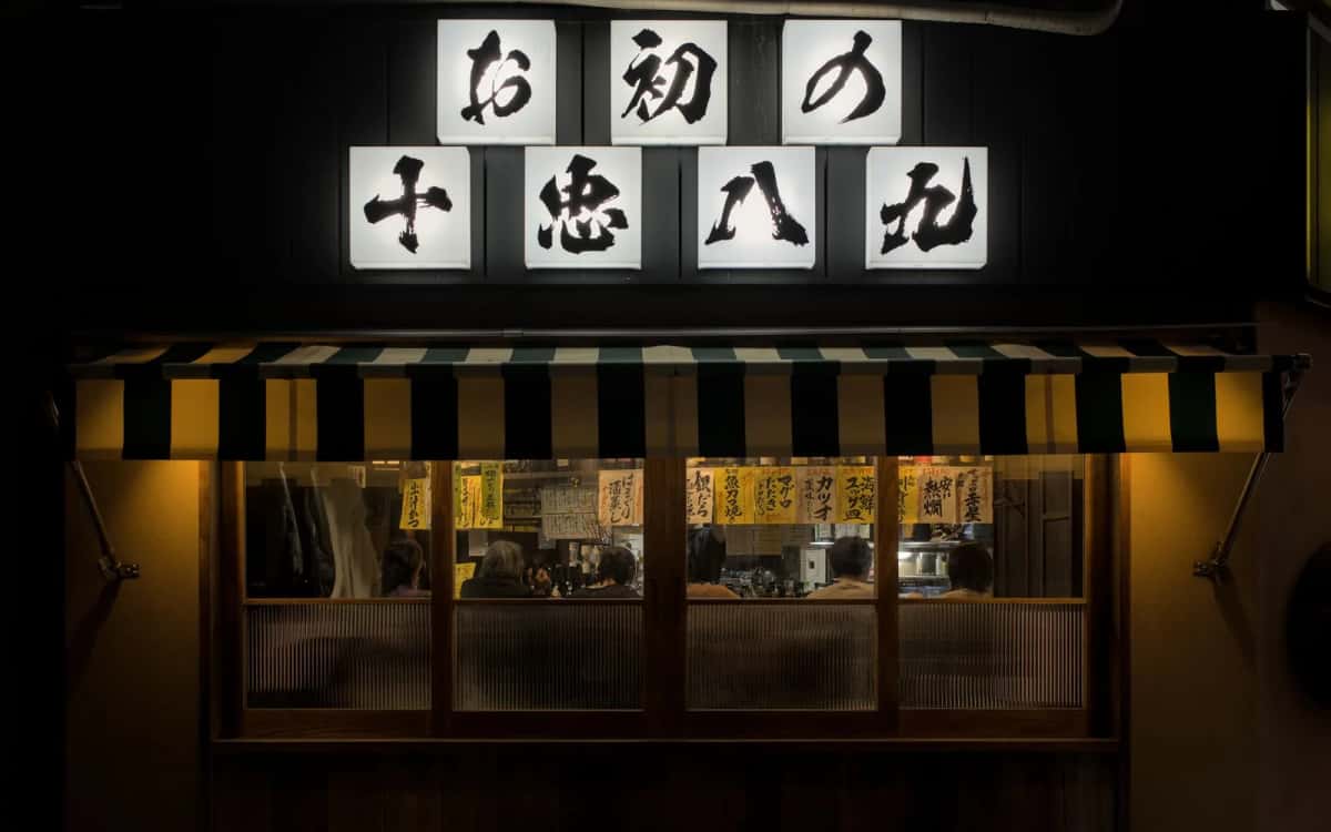 Devanture d'izakaya japonais couverte d'enseignes calligraphiées et de menus manuscrits