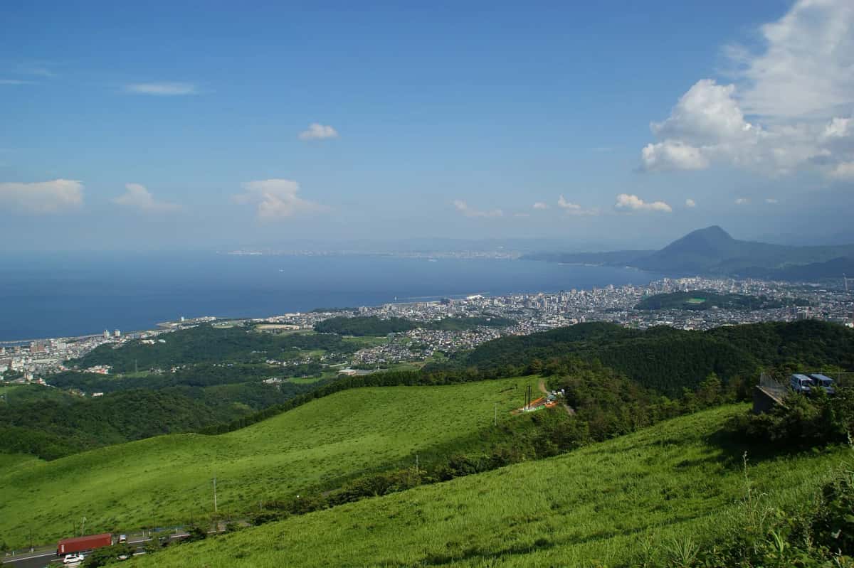 La ville de Beppu et sa baie vues depuis les collines herbeuses au-dessus de la ville, avec le mont Takasaki à l'horizon