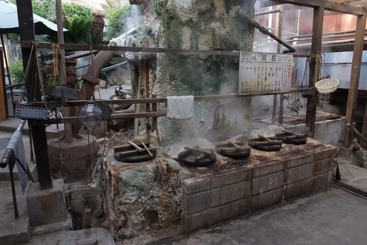 Fours à vapeur de source fermés par des couvercles en bois, dans une cour fumante du quartier de Kannawa à Beppu