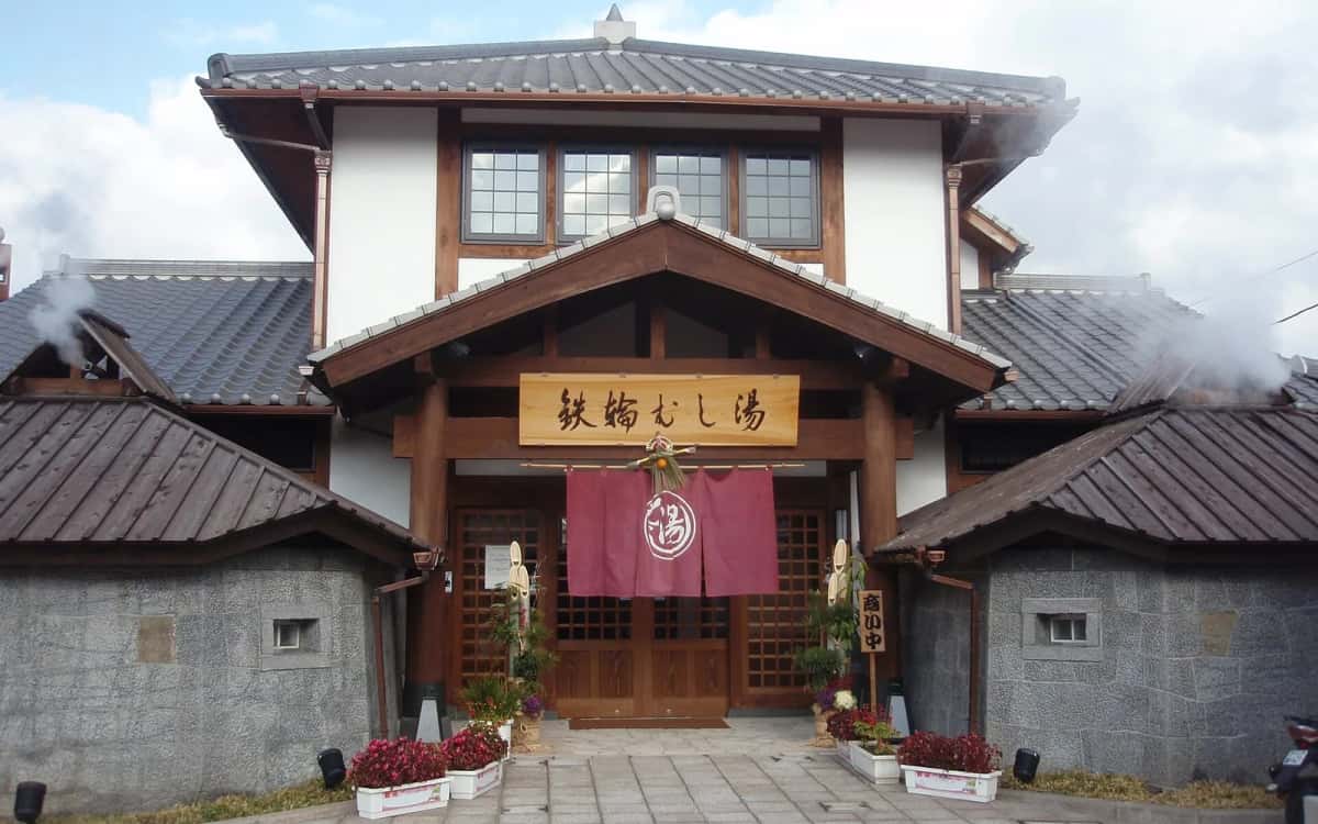 Entrée de Kannawa Mushiyu, le bain de vapeur de Beppu, avec son rideau bordeaux et de la vapeur qui s'échappe des toits