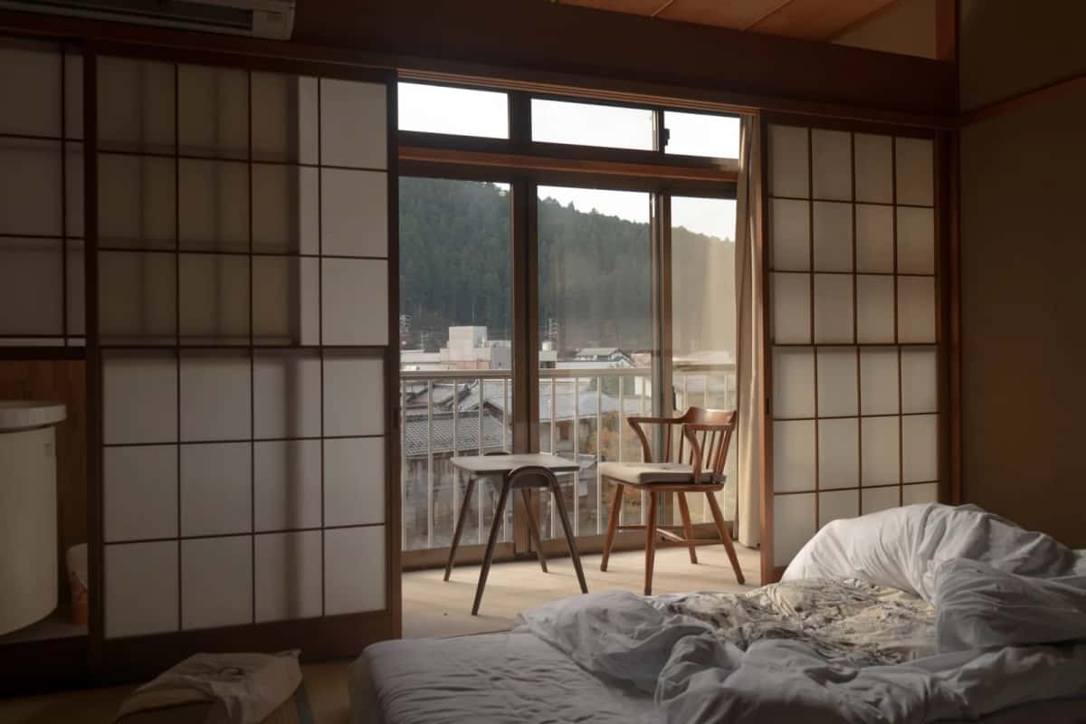 Chambre de ryokan japonais avec tatamis, cloisons shoji et futon, donnant sur une véranda et des toits de tuiles (illustration, pas à Beppu)