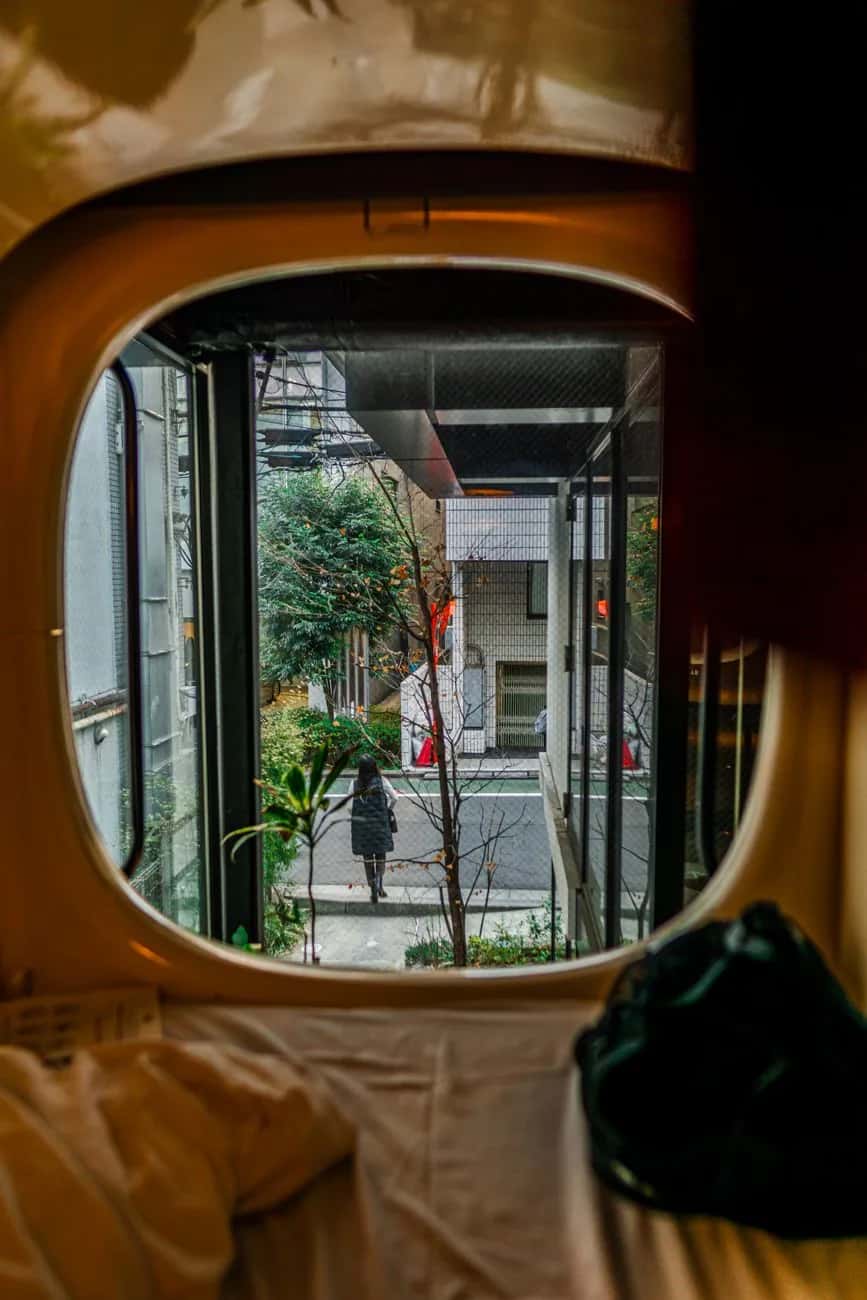 Intérieur d'un capsule hotel à Tokyo, vue depuis le pod sur une ruelle japonaise