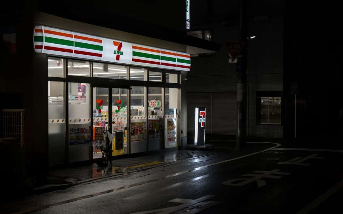Konbini 7-Eleven éclairé la nuit dans une rue mouillée de Kyoto, au Japon