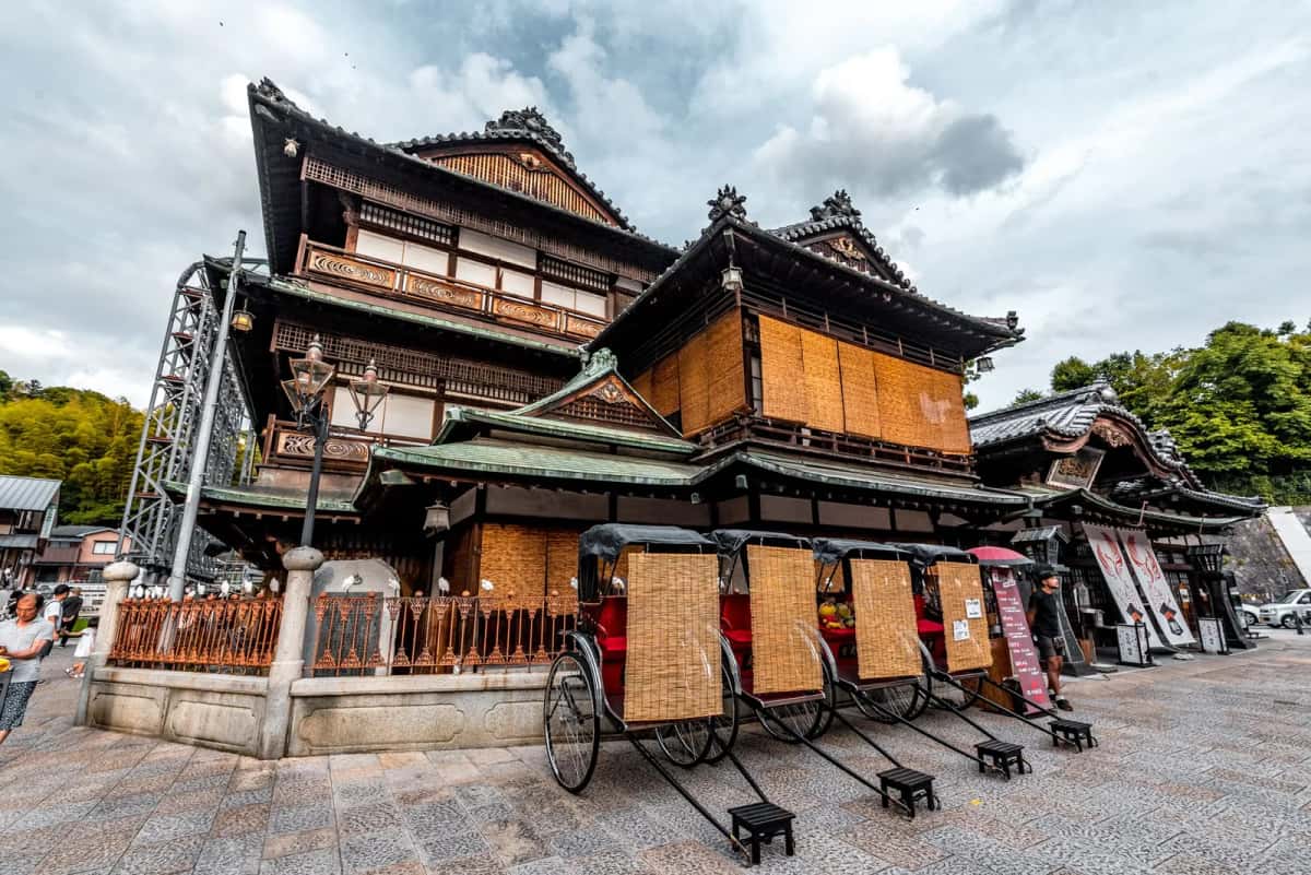 Bâtiment en bois du Dogo Onsen Honkan et pousse-pousse devant les bains, Matsuyama, Shikoku
