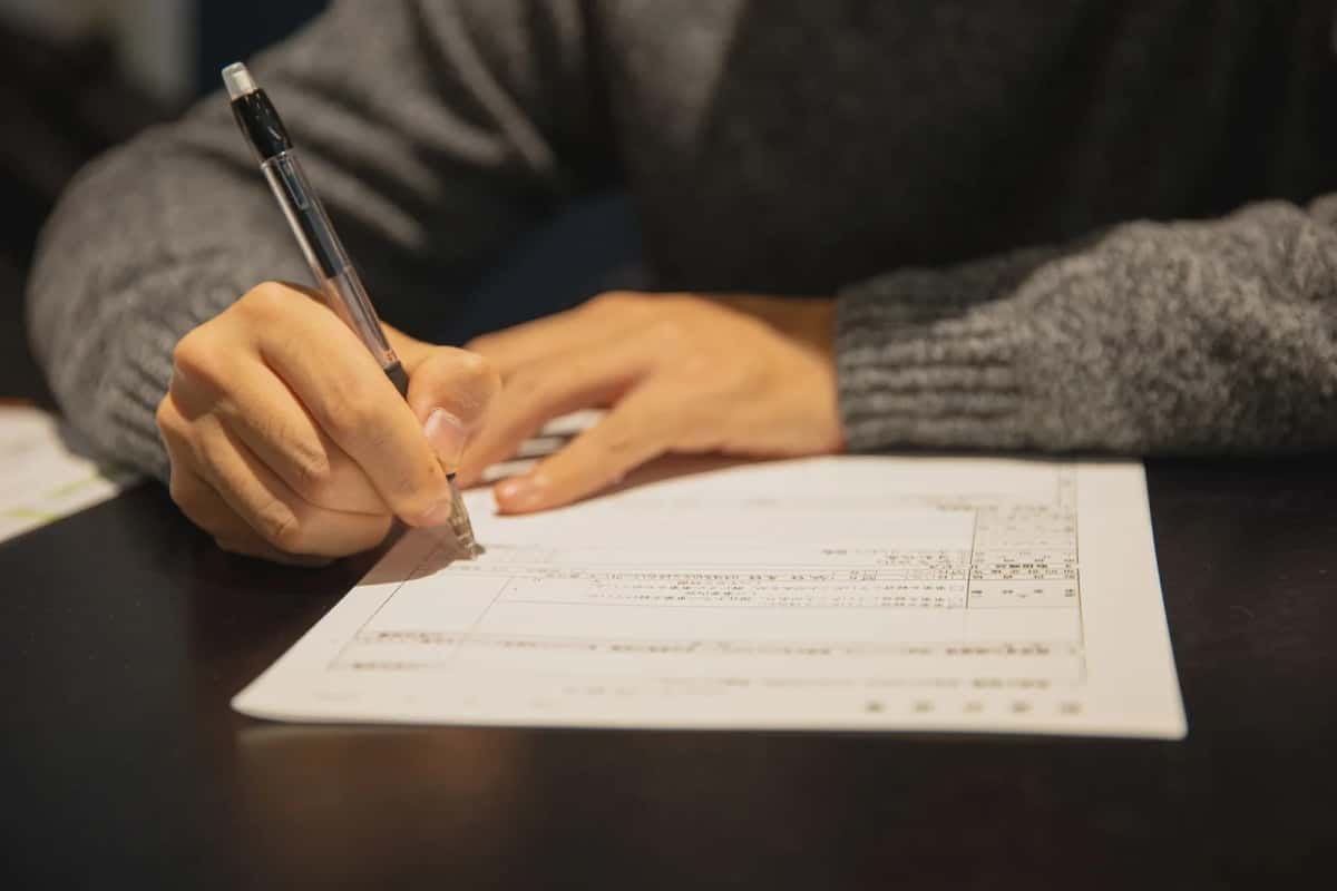 Personne remplissant au stylo un formulaire administratif japonais