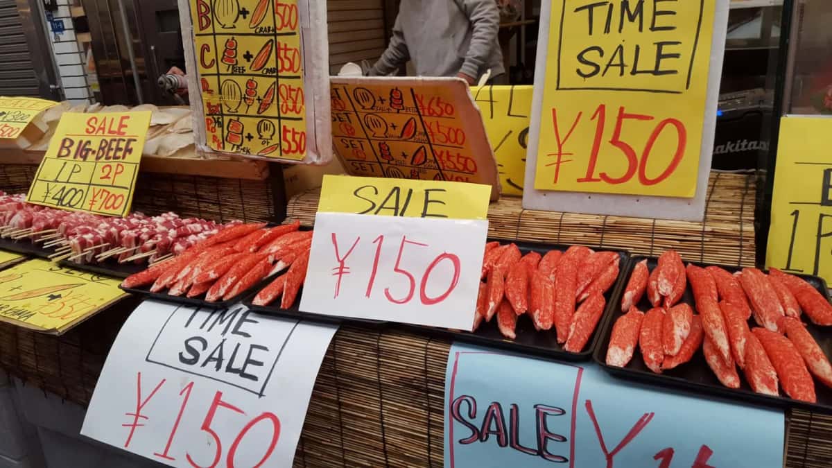 Étiquettes de prix en yens écrites à la main sur un étal de marché alimentaire au Japon
