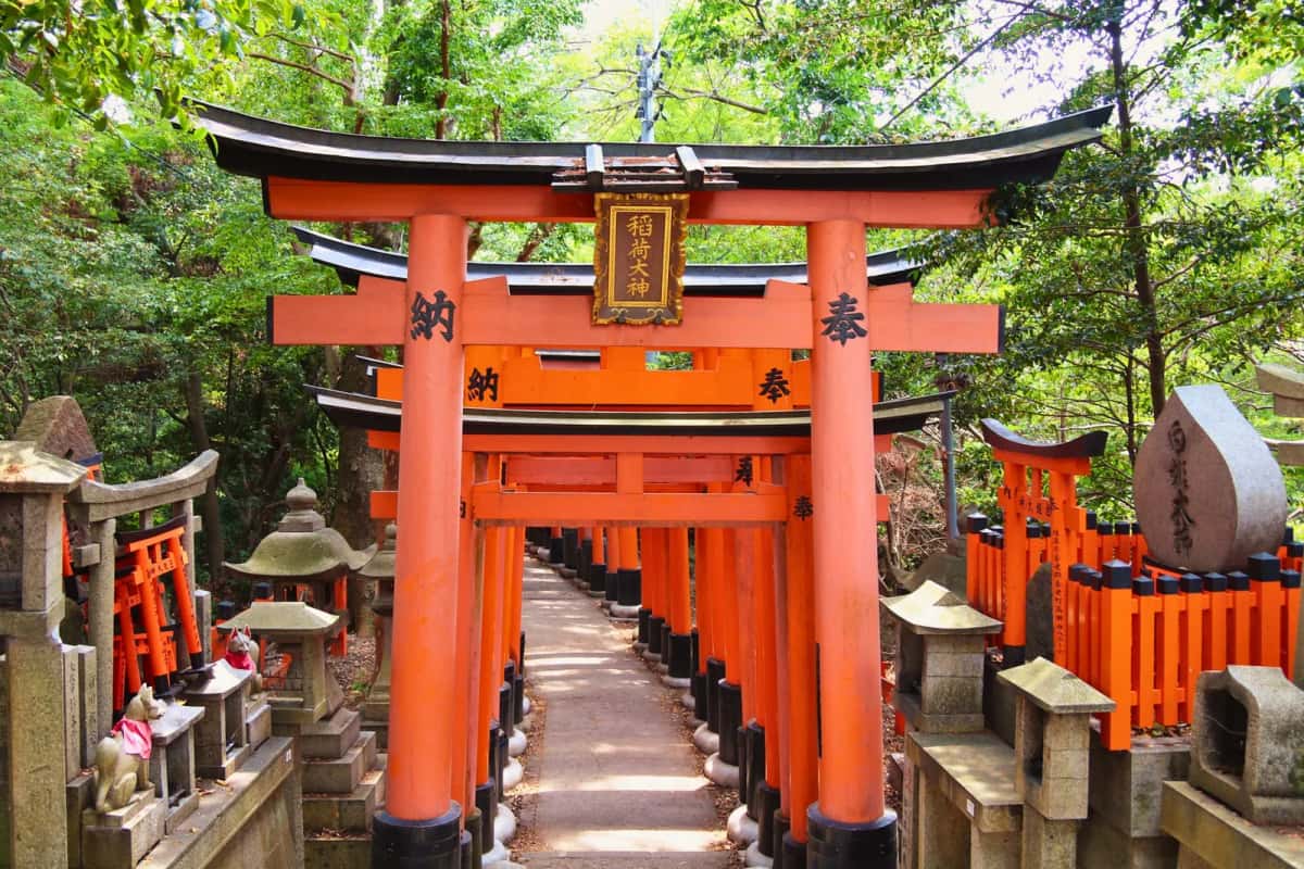 Allée de torii vermillon sur le sentier du mont Inari, avec statues de renards, à Kyoto