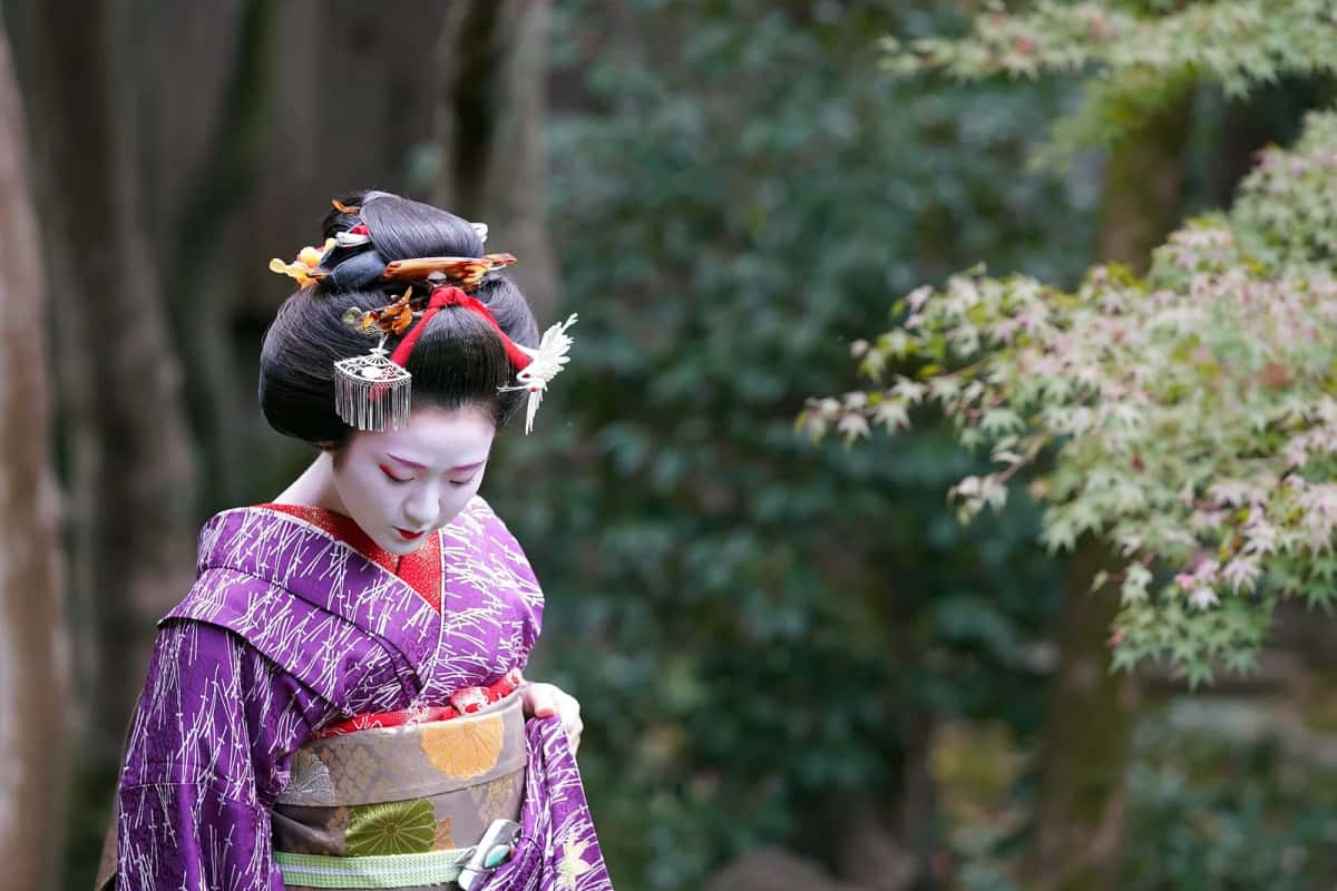 Maiko de Gion Higashi vue de trois quarts arrière, coiffure ornée de kanzashi et col rouge