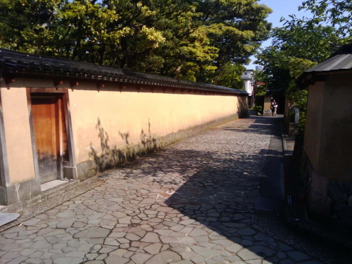 Une ruelle du quartier des samouraïs Nagamachi à Kanazawa, longée de murs en terre jaune et d'un petit canal
