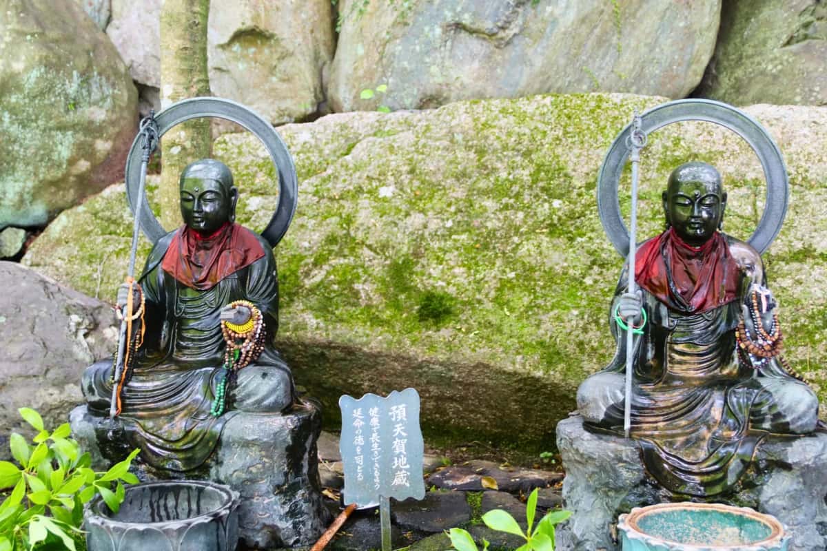 Deux statues de jizo à auréole sur des rochers moussus au temple Daisho-in, Miyajima
