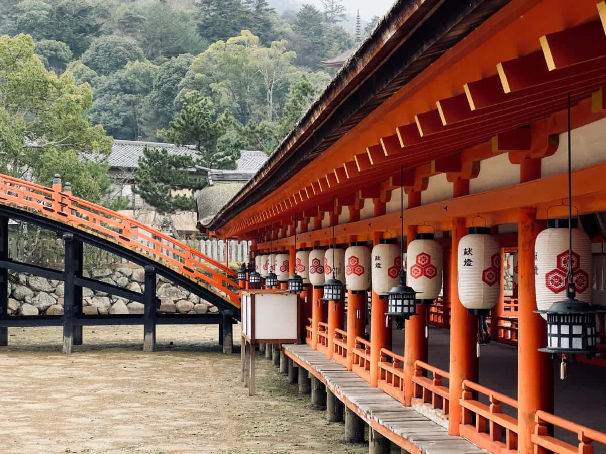 Galerie du sanctuaire d'Itsukushima bordée de lanternes blanches, avec un pont arqué, Miyajima