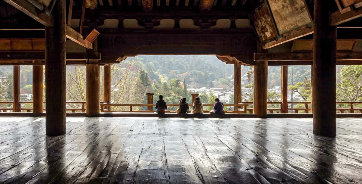 Intérieur du grand hall en bois du Senjokaku, avec des visiteurs assis face à la vue sur Miyajima