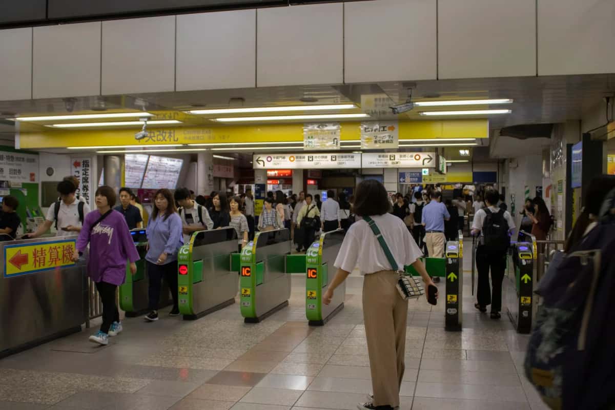 Voyageurs franchissant les portillons marqués IC d'une gare de Tokyo aux heures de pointe