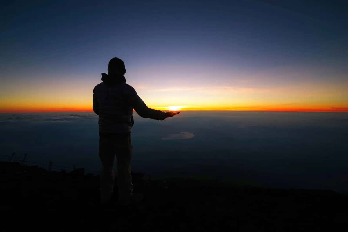 Grimpeur au sommet du Mont Fuji devant le lever de soleil au-dessus des nuages (goraiko)