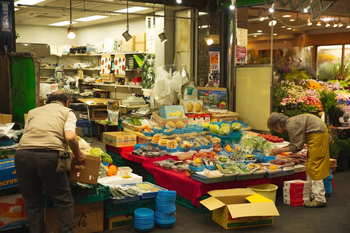 Commerçants installant leur étal de fruits et légumes dans un marché couvert d'Osaka