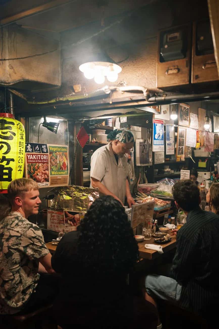 Clients attablés au comptoir d'un izakaya à yakitori de Tokyo face au cuisinier
