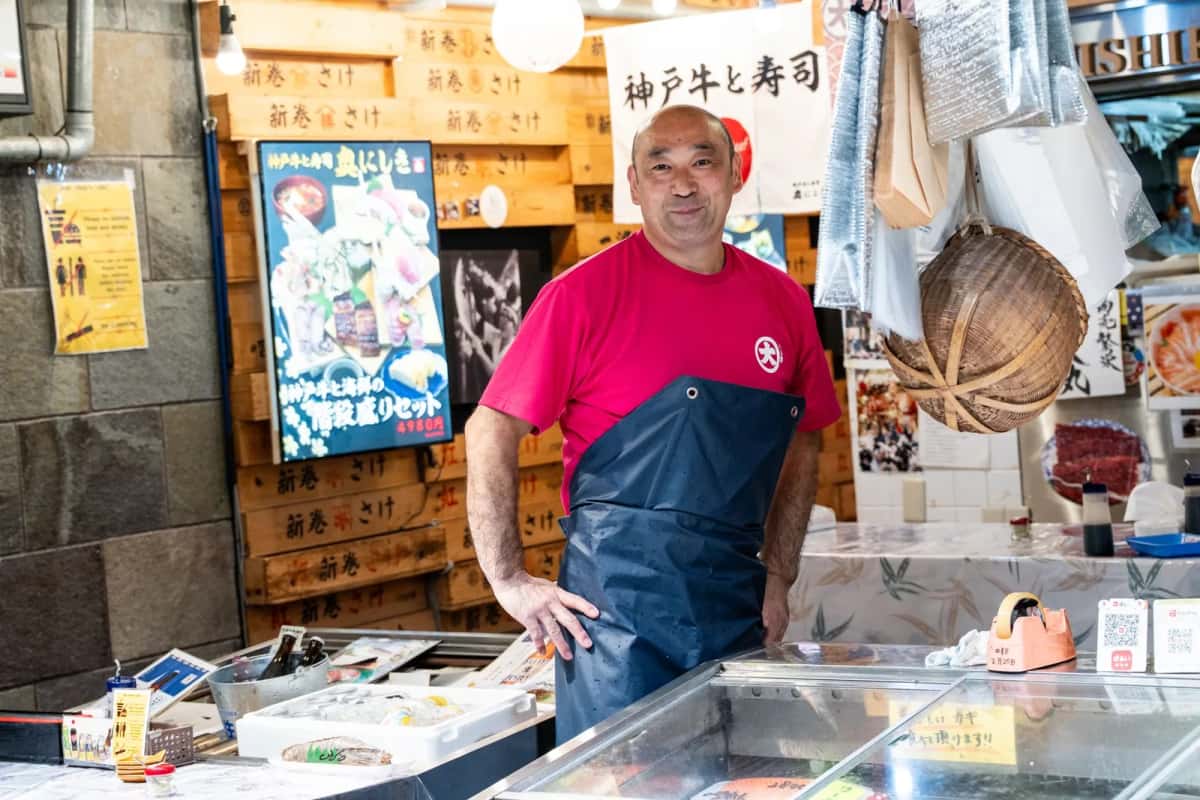 Poissonnier souriant derrière son étal dans un marché couvert japonais