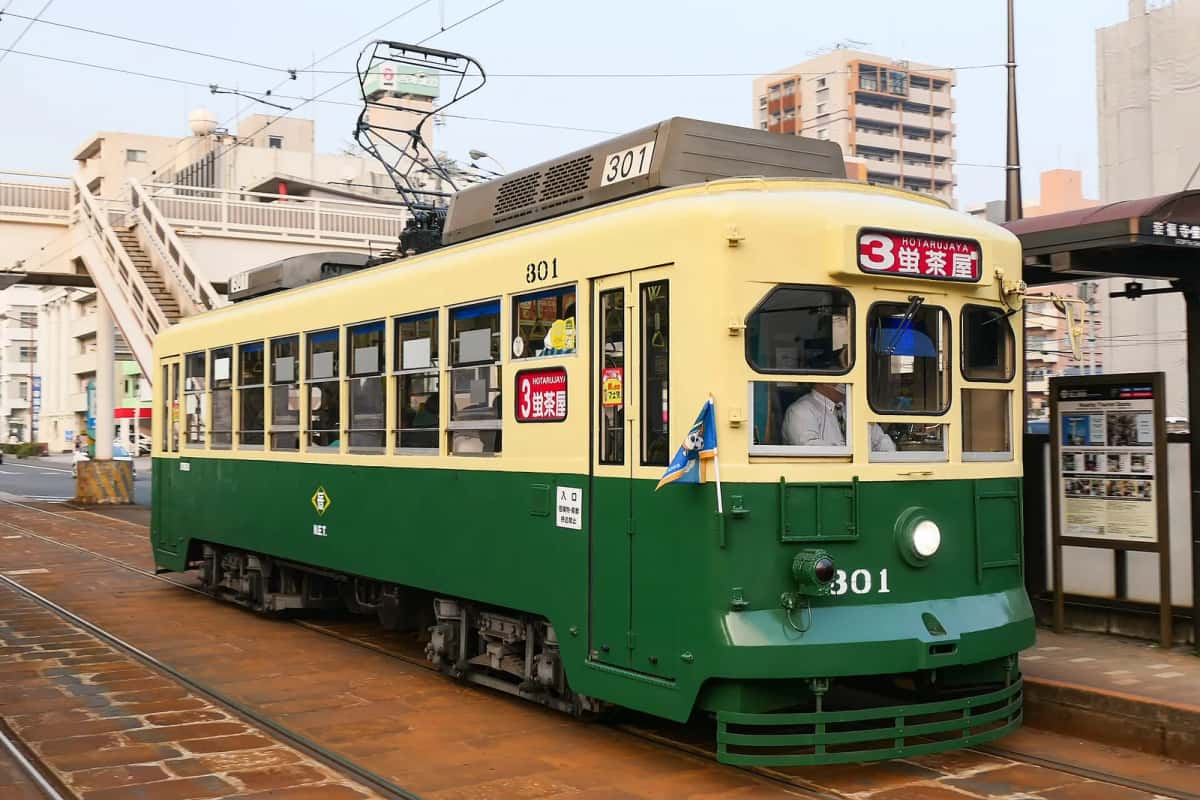 Un tramway vert et crème de Nagasaki à un arrêt de la ville