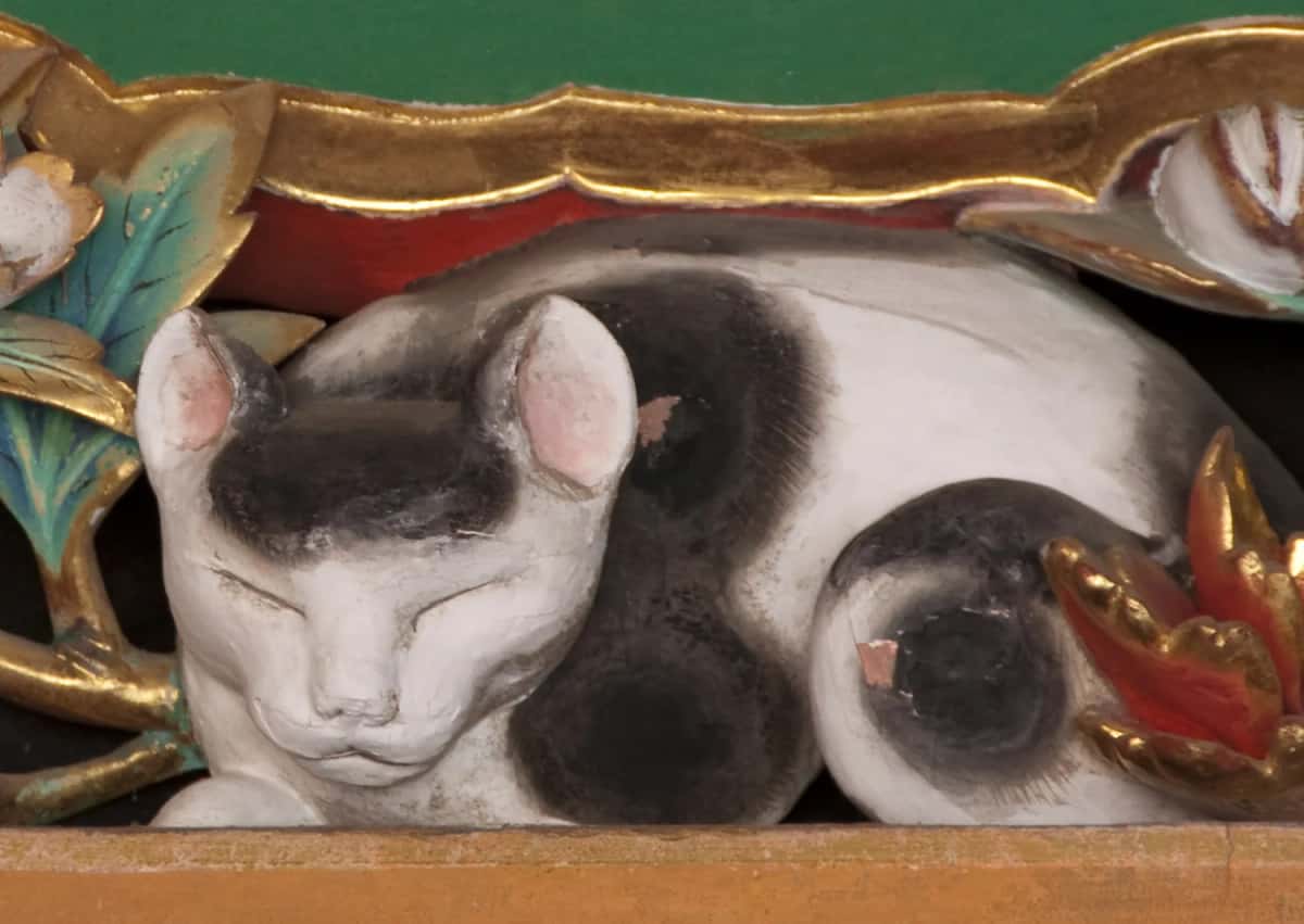 Le Nemuri-neko, petit chat blanc et noir sculpté endormi parmi des pivoines, au-dessus d'un passage du Tōshō-gū de Nikko