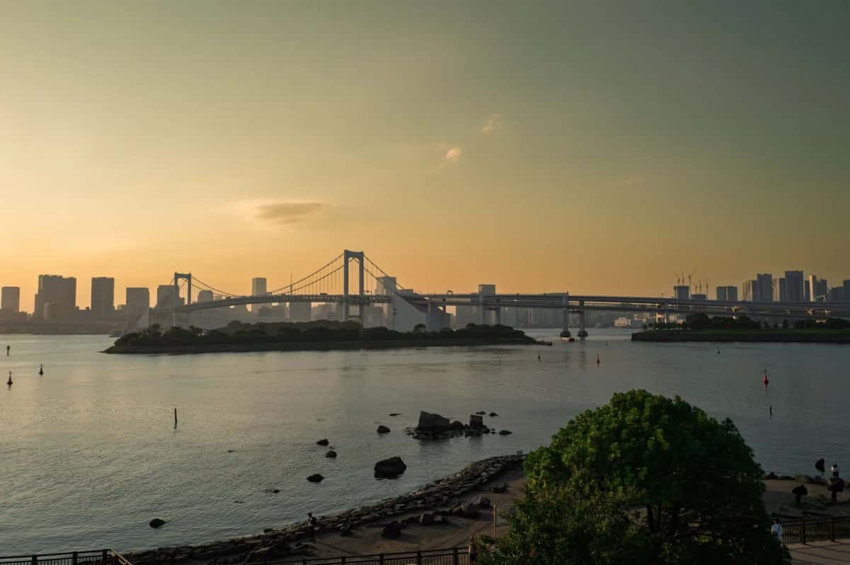 Coucher de soleil sur la baie de Tokyo depuis le front de mer d'Odaiba, avec le Rainbow Bridge et les tours de Minato à l'horizon