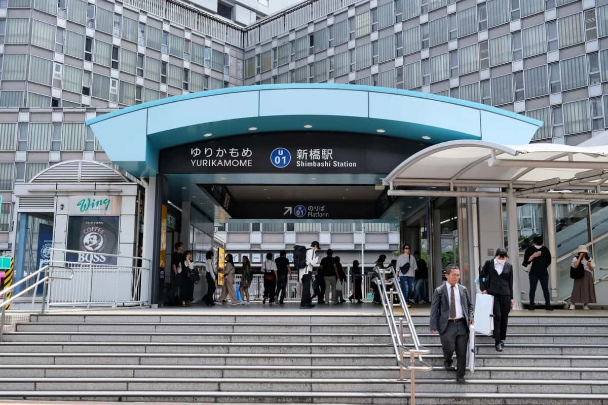 Entrée de la gare Yurikamome de Shimbashi, marquée U01, avec des voyageurs dans l'escalier