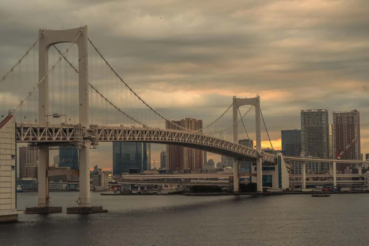 Les deux pylônes blancs du Rainbow Bridge au-dessus de la baie de Tokyo en fin de journée, devant les tours de Minato