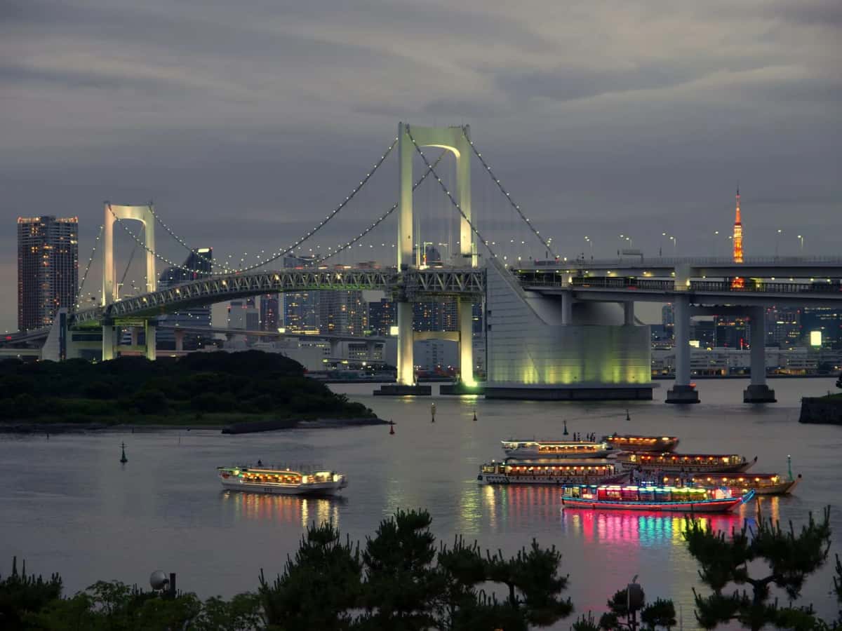 Bateaux yakatabune illuminés sous le Rainbow Bridge au crépuscule, dans la baie de Tokyo à Odaiba