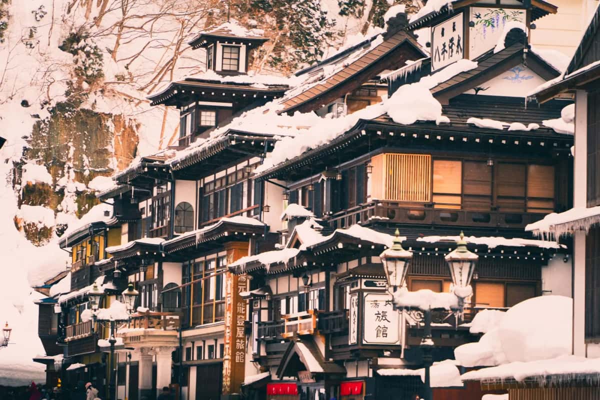 Ryokan en bois sous la neige et lanternes allumées à Ginzan Onsen en hiver