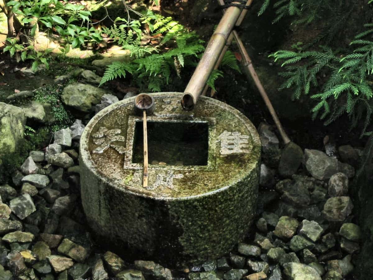 Le tsukubai du Ryoan-ji à Kyoto, bassin de pierre rond au trou carré entouré de caractères gravés