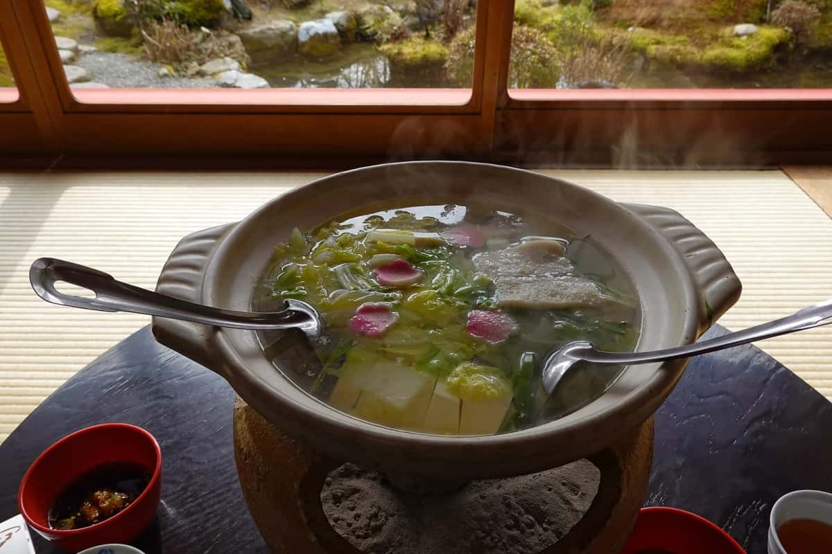 Pot de yudofu fumant servi au Ryoan-ji à Kyoto, jardin visible derrière la baie
