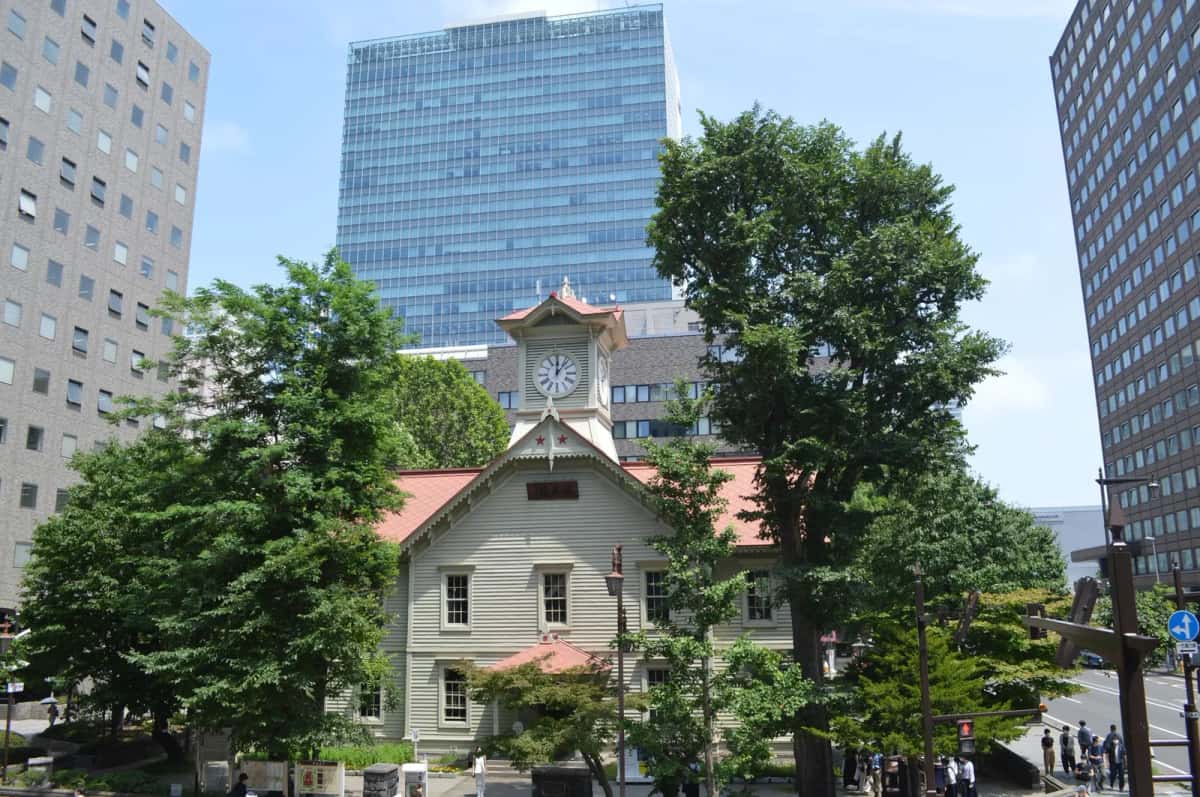 La tour de l'horloge (Tokeidai) de Sapporo entourée d'immeubles et d'arbres