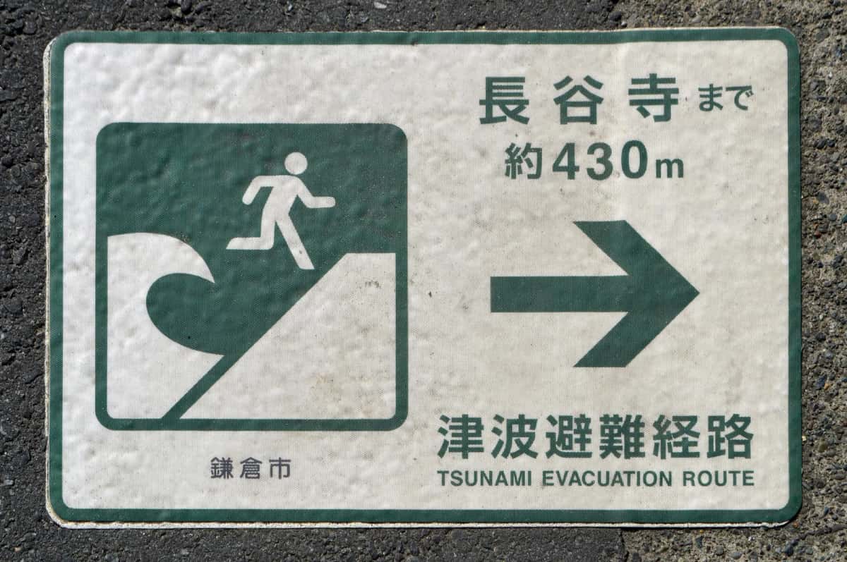 Panneau bilingue d'itinéraire d'évacuation tsunami peint sur la chaussée à Kamakura, indiquant le temple Hase-dera à 430 m