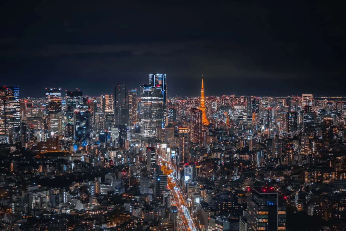 Tokyo de nuit vue d'en haut, avec la Tokyo Tower illuminée et une avenue éclairée au premier plan