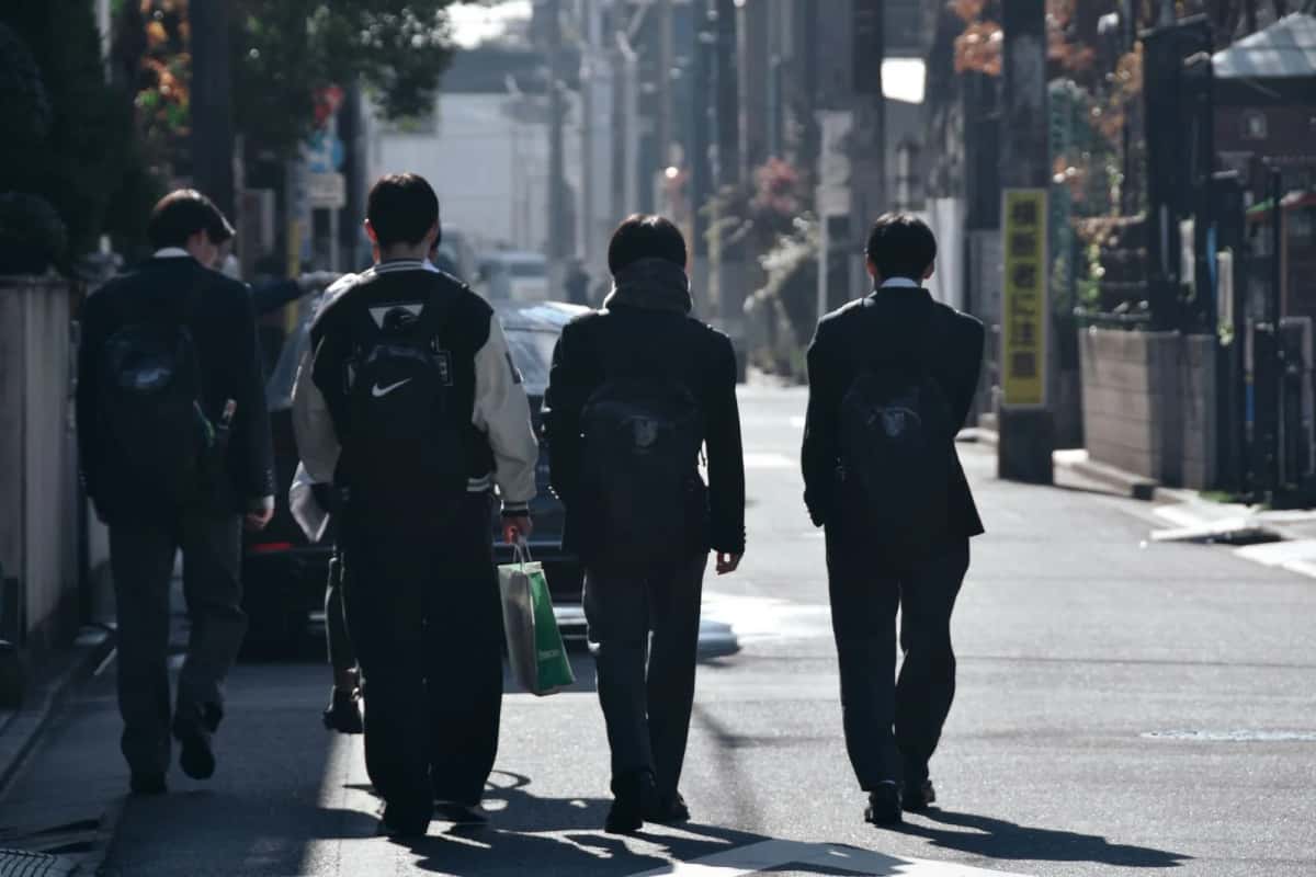 Lycéens japonais en uniforme vus de dos dans une rue de ville au Japon