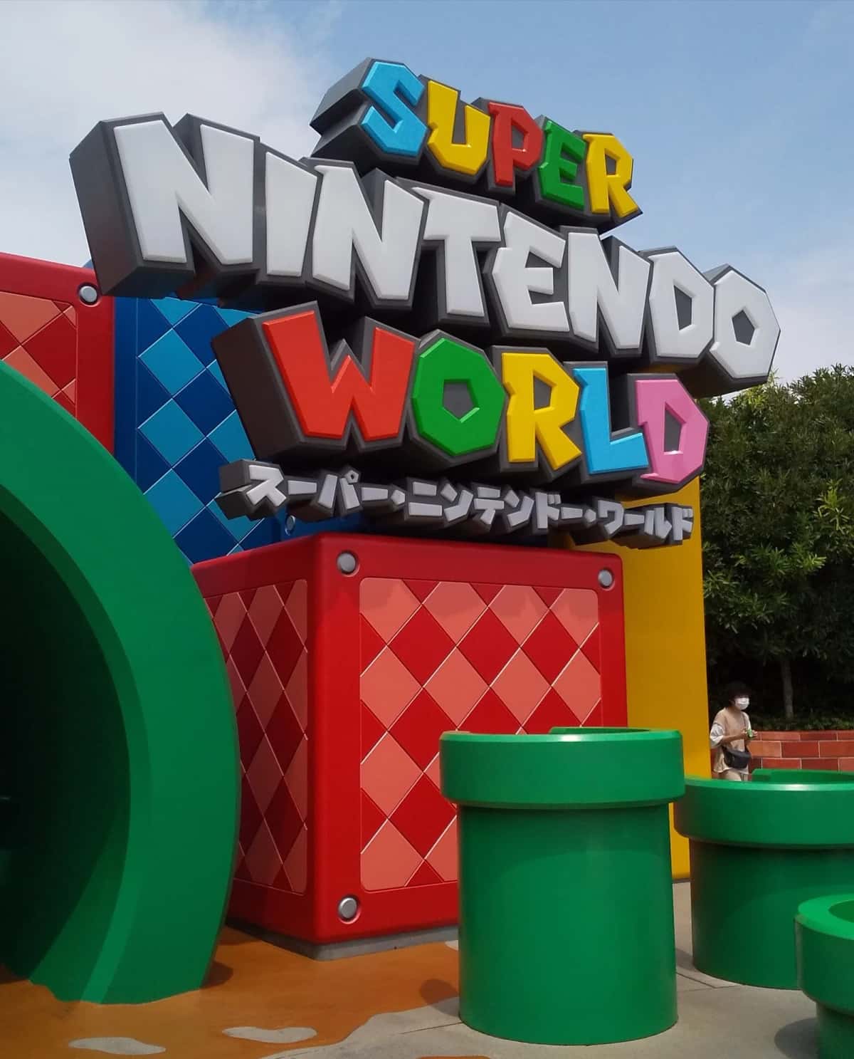 L'enseigne Super Nintendo World en lettres colorées au-dessus des tuyaux verts, à l'entrée de la zone à Universal Studios Japan