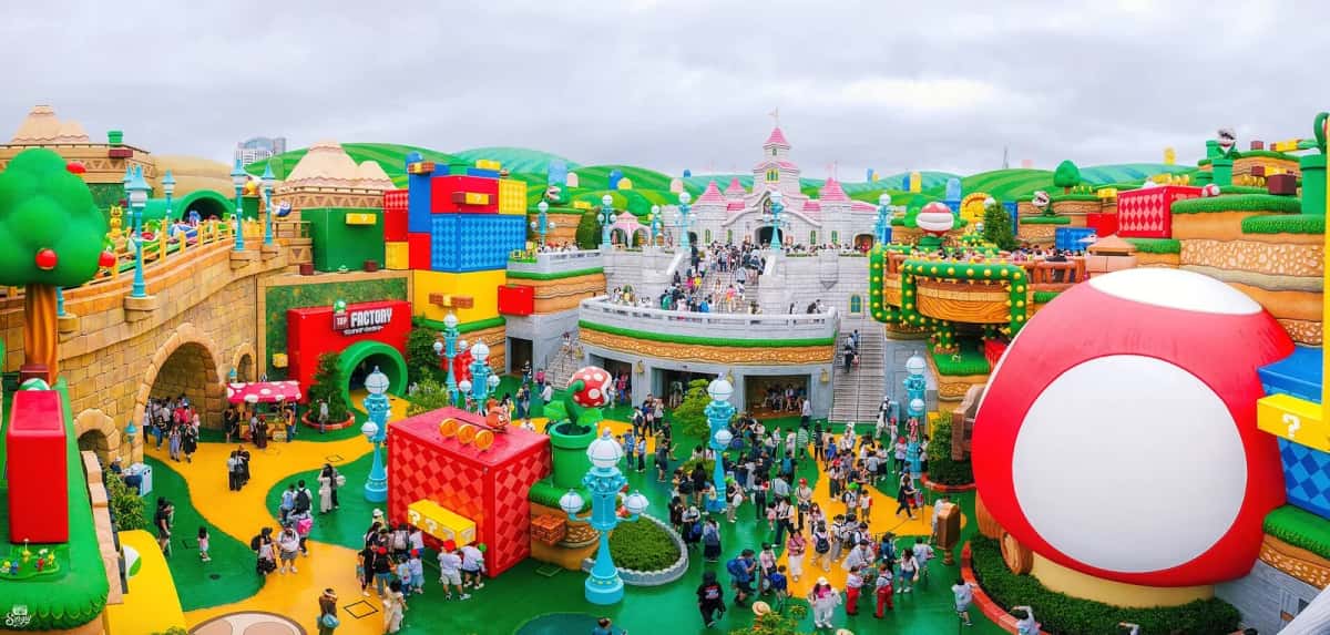La foule sur les places de Super Nintendo World à Osaka, vue d'en haut, entre les blocs géants et le champignon rouge
