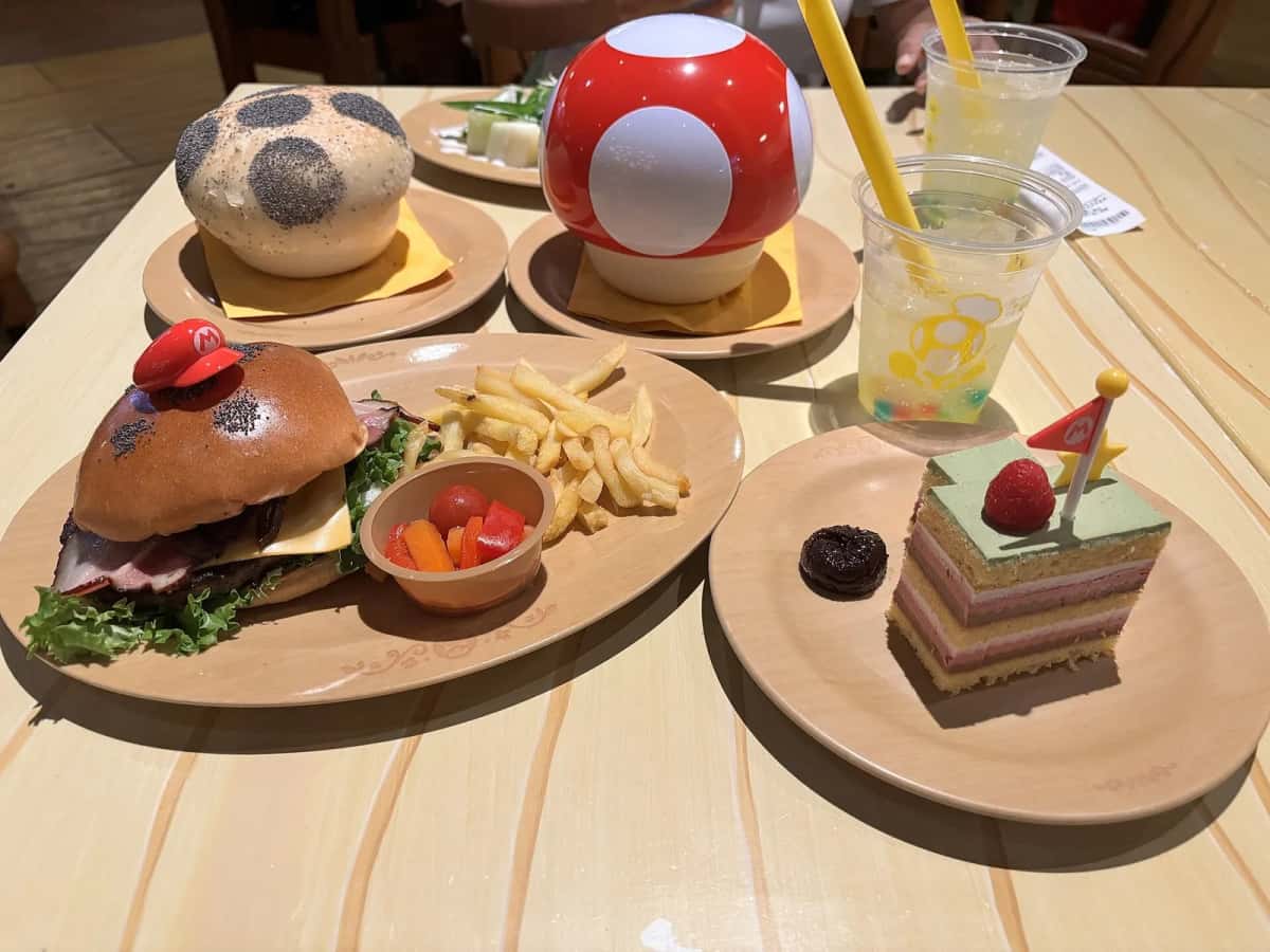 Un burger au chapeau de Mario, des frites, un gâteau et une boisson servis au Kinopio's Cafe de Super Nintendo World, Osaka