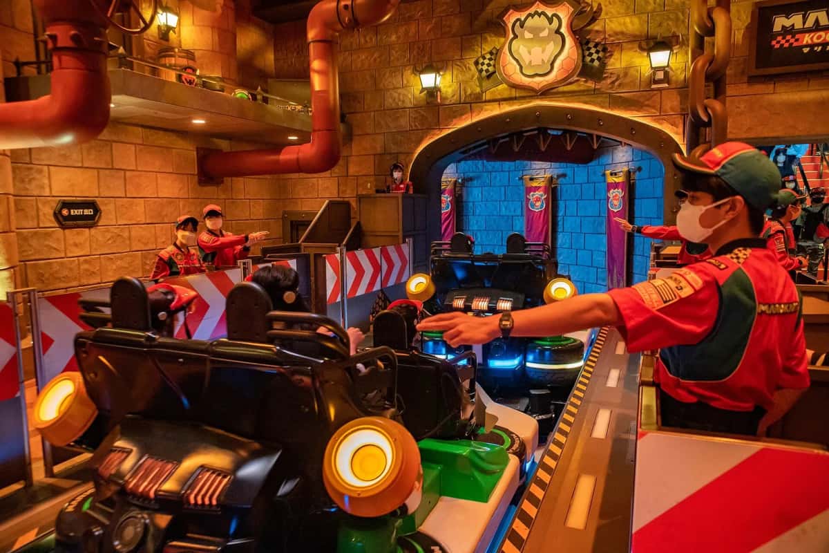 Un agent de Mario Kart: Koopa's Challenge vérifie un kart à quatre places avant le départ, à Universal Studios Japan