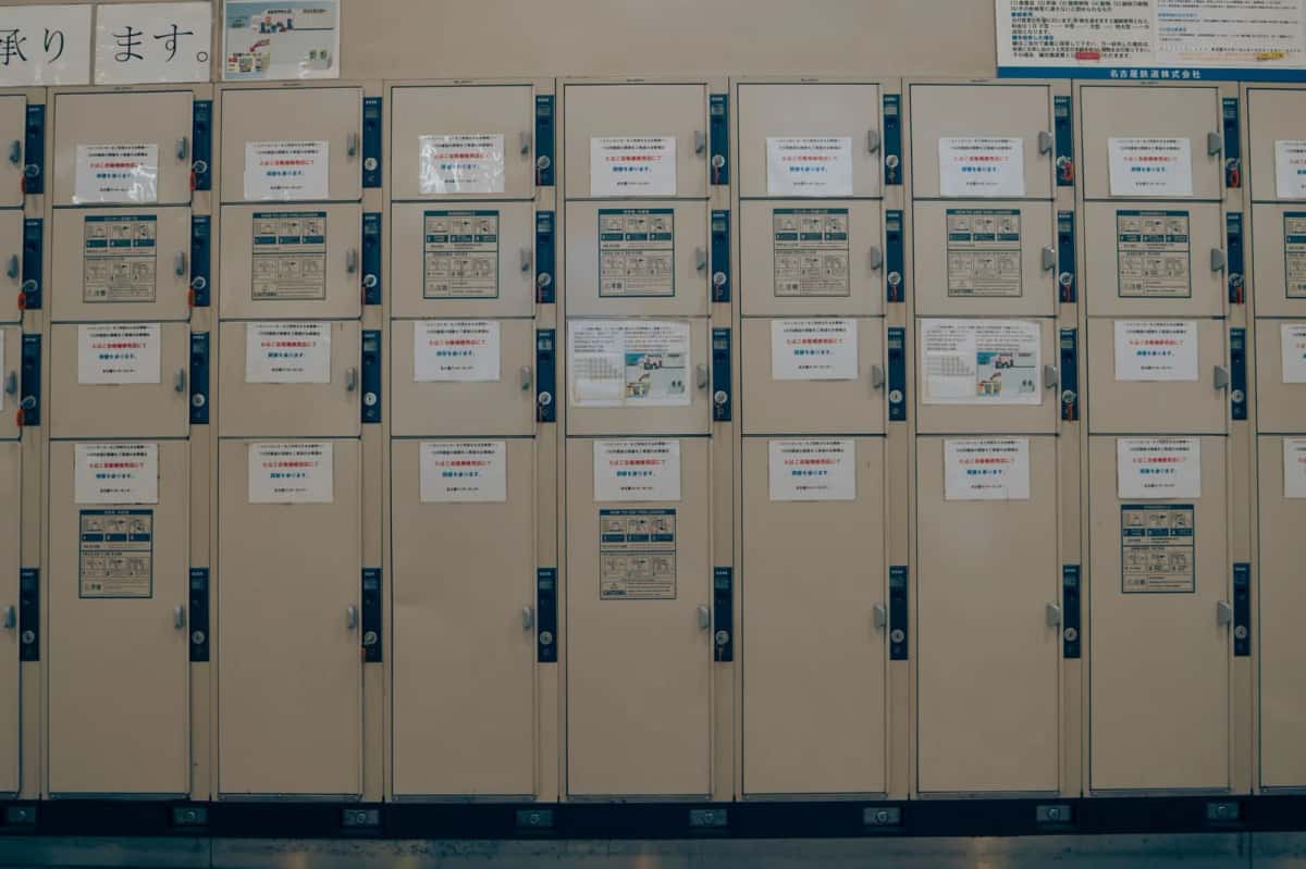 Rangée de casiers de consigne à pièces dans une gare Meitetsu de Nagoya, avec les instructions affichées sur les portes