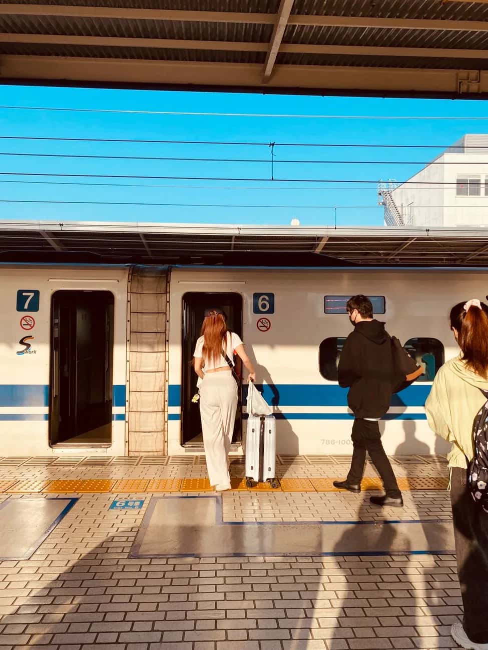 Voyageuse tirant une valise rigide en montant dans un Shinkansen à quai, voiture 6