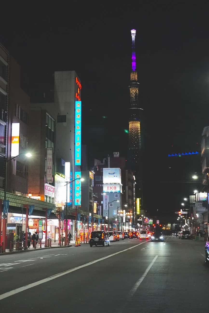 La Tokyo Skytree illuminée en violet et or au bout d'une avenue commerçante, la nuit