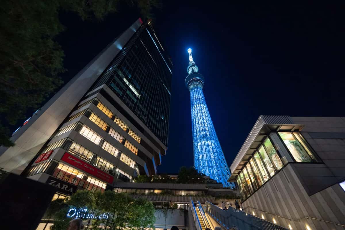 Entrée du centre commercial Tokyo Solamachi la nuit, au pied de la Skytree illuminée en bleu