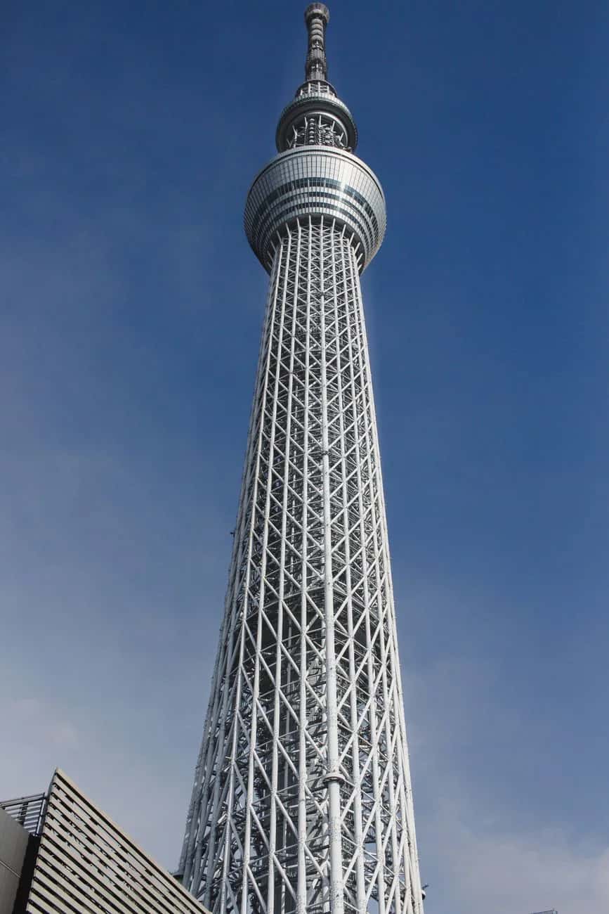 Le treillis d'acier blanc et l'observatoire circulaire de la Tokyo Skytree en contre-plongée, sur un ciel bleu