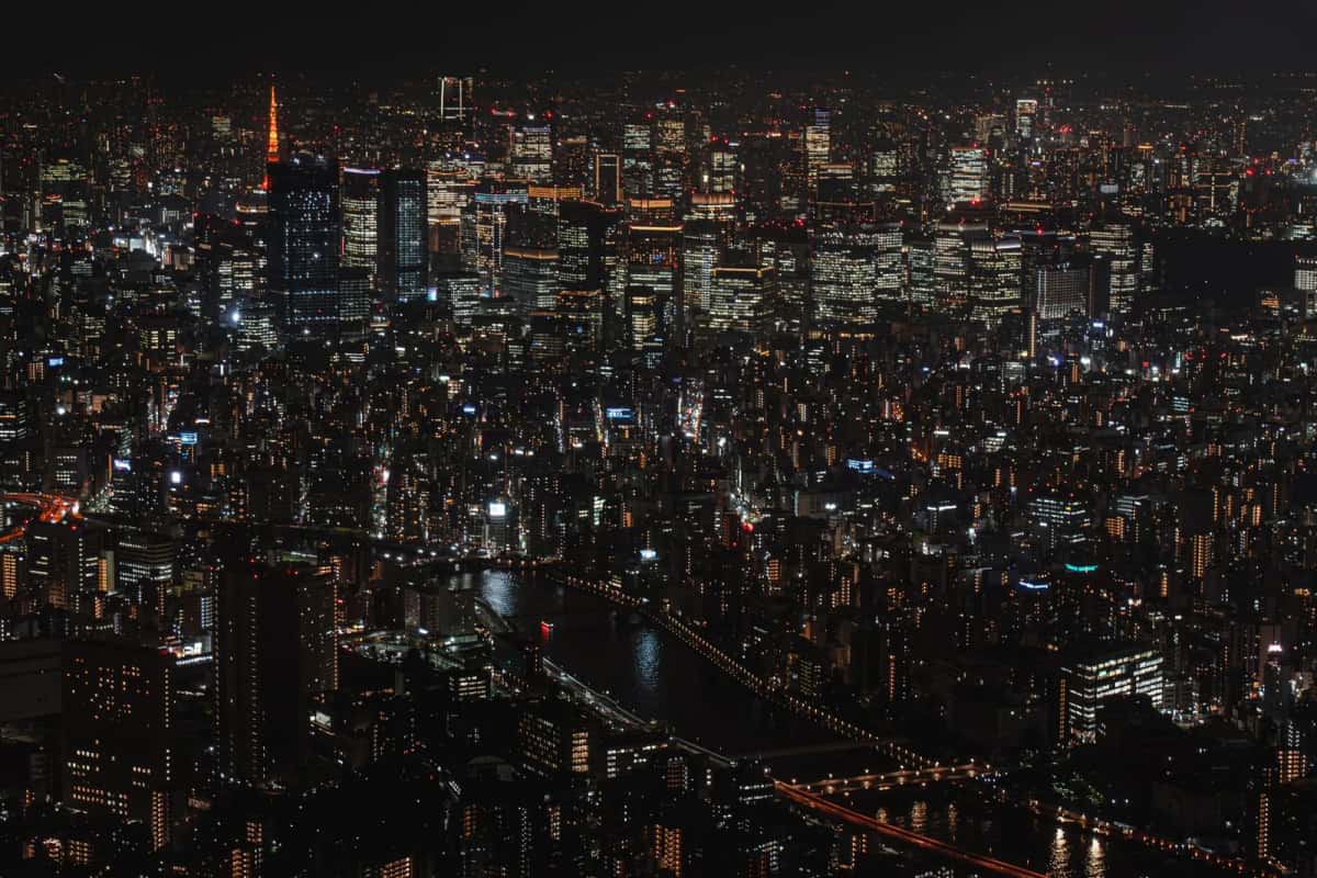Tokyo illuminé la nuit vu depuis la Skytree, avec la Sumida au premier plan et la Tokyo Tower rouge au loin