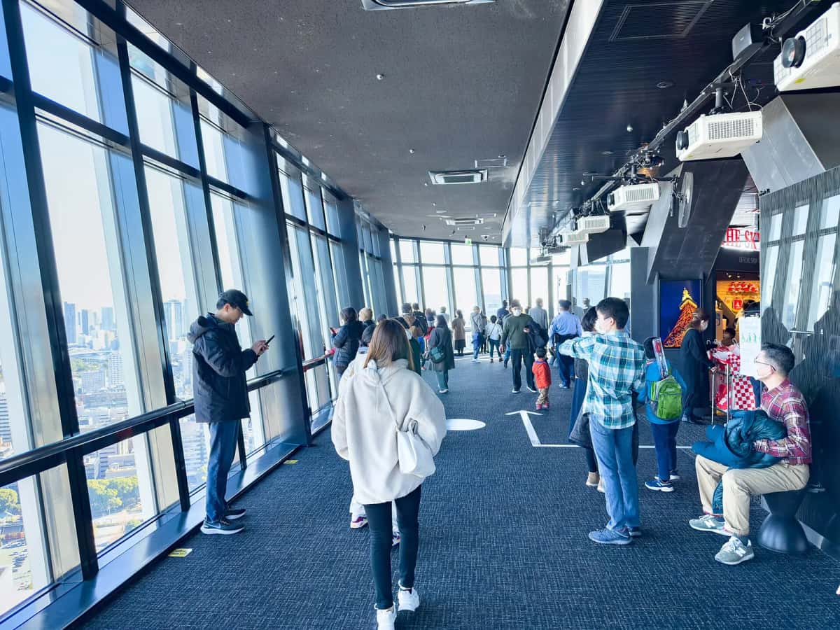 Visiteurs dans le couloir vitré du Main Deck de la Tokyo Tower, à 150 m, avec la ville en contrebas