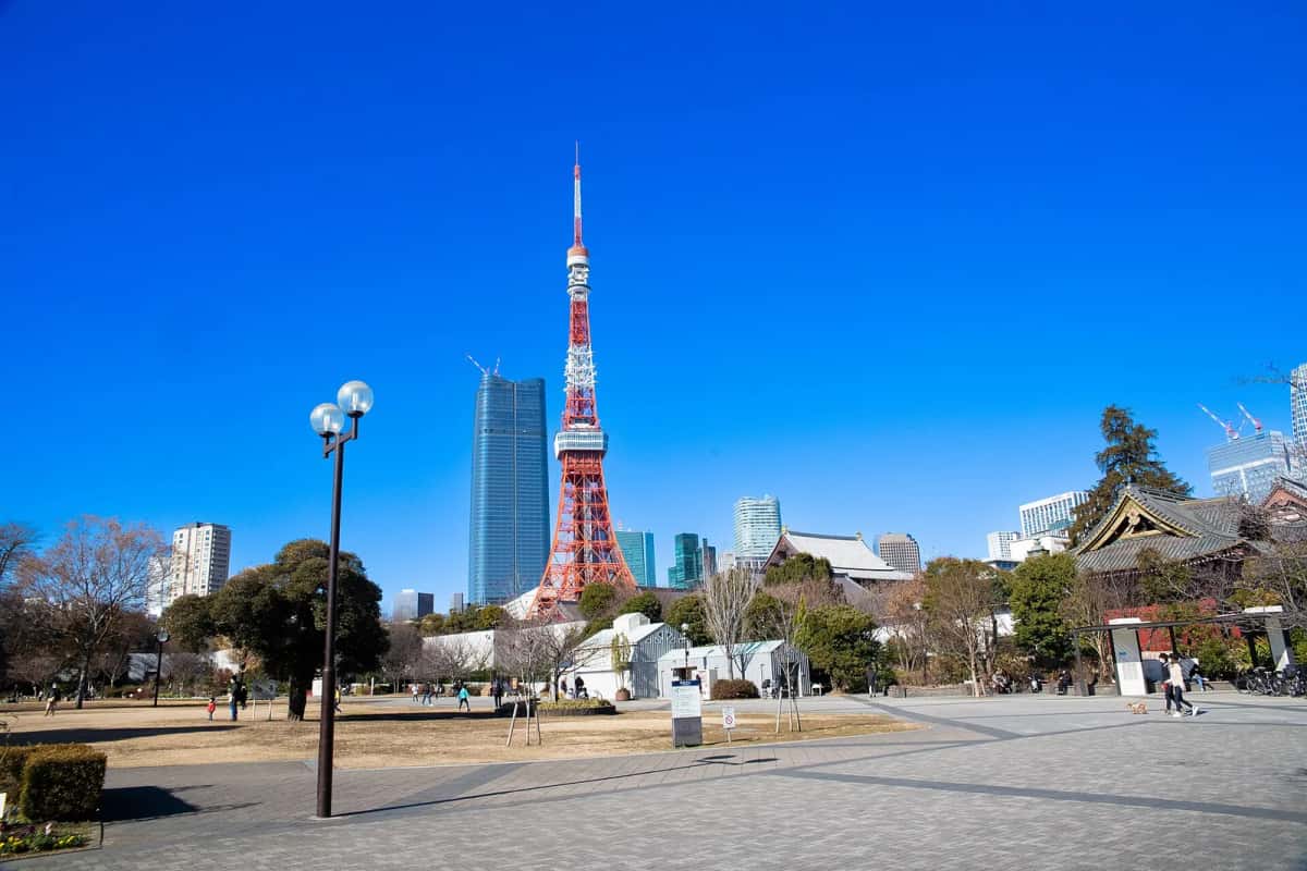La Tokyo Tower vue depuis le parc Shiba à Minato, avec les pelouses et un toit du Zojo-ji