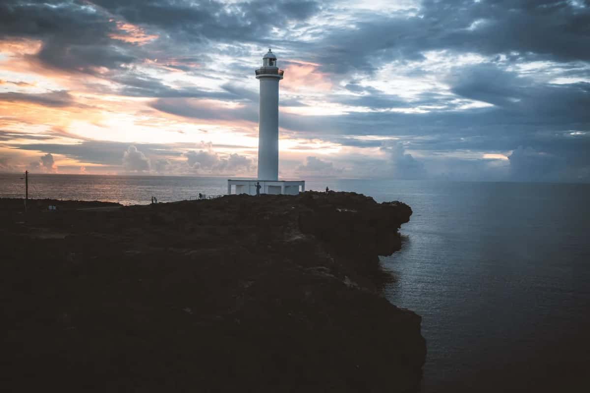Phare sur une falaise au bord du Pacifique sous un ciel chargé de nuages sombres au crépuscule