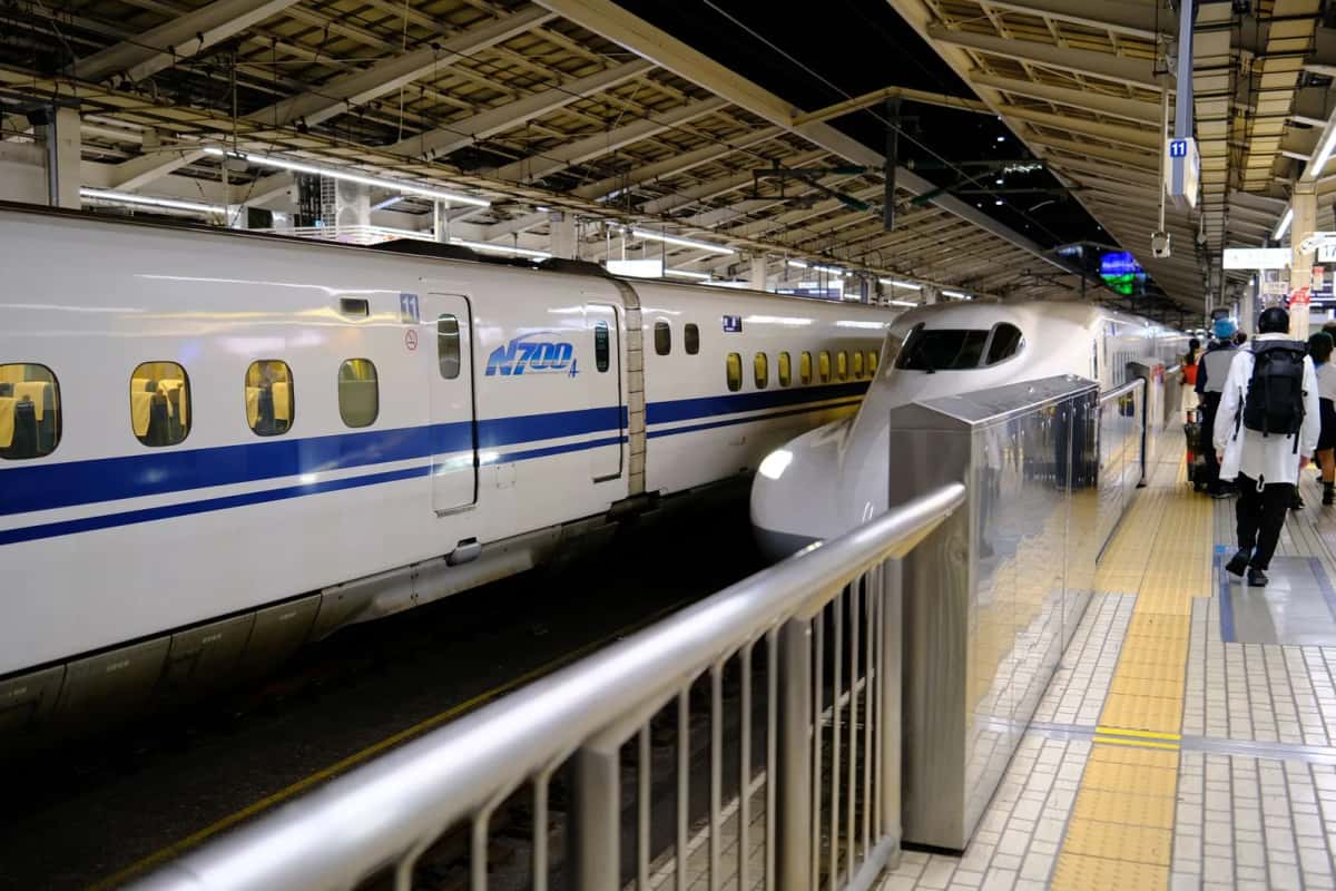 Shinkansen à quai dans une gare japonaise, un voyageur marchant sur le quai