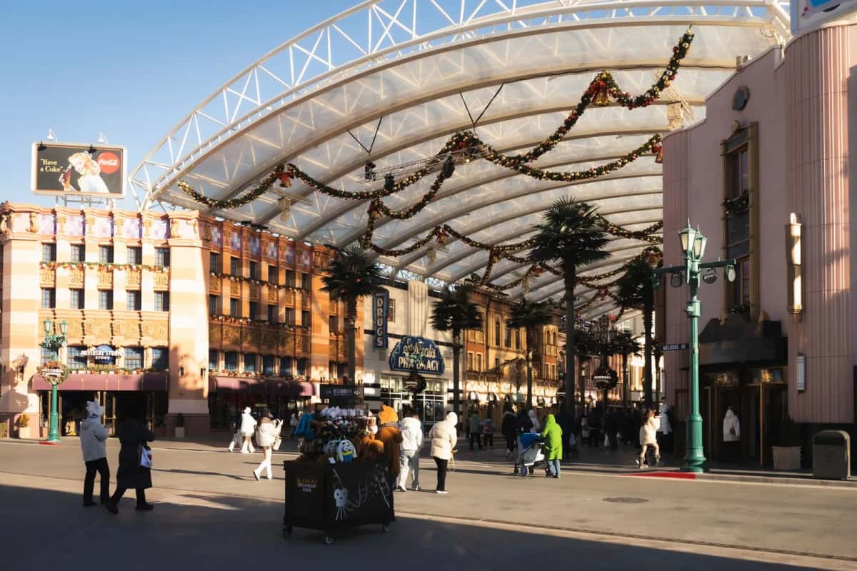 L'allée couverte de la zone Hollywood de Universal Studios Japan, décorée de guirlandes de Noël, avec des visiteurs en manteau